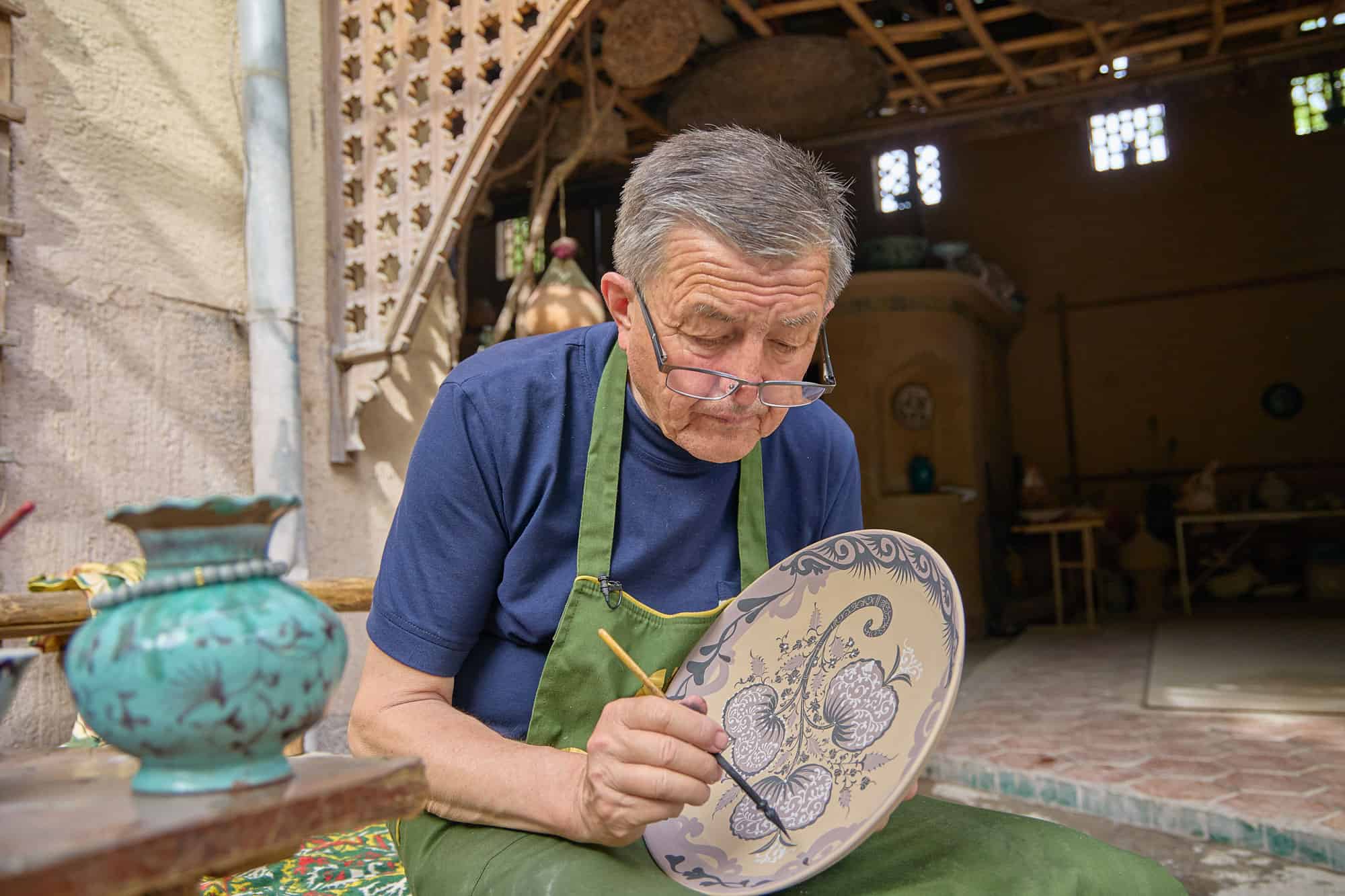A master ceramicist hand-painting a porcelain plate in Rishtan, Uzbekistan